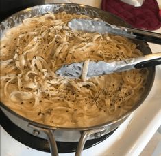 a pan filled with noodles and sauce on top of a stove