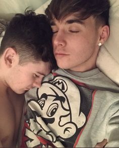 two young men laying next to each other in bed