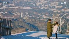 a man and woman standing on top of a snow covered slope