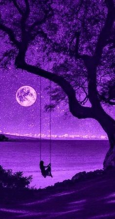 a person sitting on a swing under a tree with the moon in the sky above