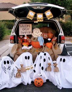 halloween decorations in the back of a car with ghost bags and pumpkins on the ground