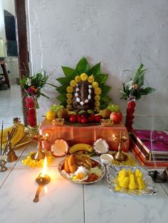 an assortment of fruits and other food on a table with candles in front of it