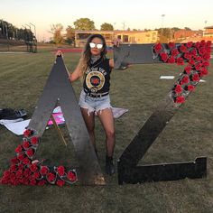 a woman standing in front of a large letter with flowers on the letters and numbers