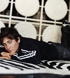 a man laying on top of a bed next to a black and white zebra print blanket