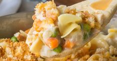 a spoon full of pasta and vegetables being lifted from a casserole dish in a skillet