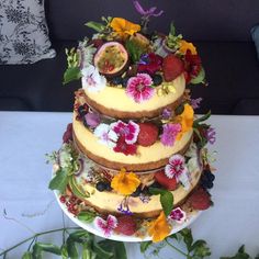 a three tiered cake with fresh fruit and flowers on top