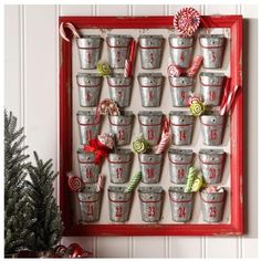 an old red frame is filled with buckets and candy canes