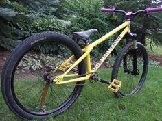 a yellow bike parked in the grass next to trees