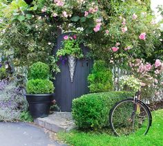 a bicycle is parked in front of a house with flowers growing on the side of it