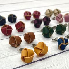 several pairs of leather cufflinks on white wooden table with rings in different colors