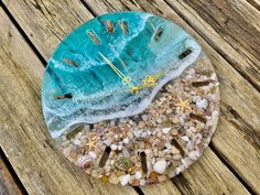 a clock that is sitting on top of some rocks and sand next to the ocean