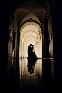 a bride and groom are standing in an archway at their wedding day, with the light reflecting on the floor