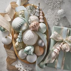 christmas ornaments are arranged on a platter next to a gift wrapped in satin ribbon