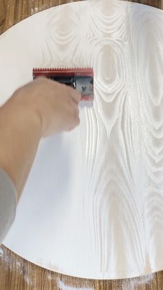 a person is using a brush to paint a piece of white paper on a table