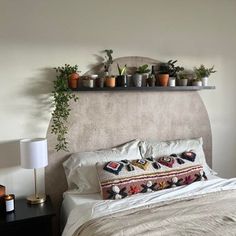 there is a bed with plants on the headboard and pillows in front of it