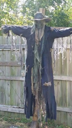 a scarecrow with his arms spread out in the air, standing on a tree stump