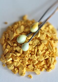 two eggs are sitting on top of some corn flakes with tongs in them