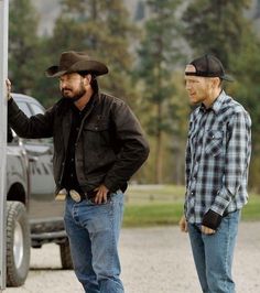 two men standing next to each other in front of a truck