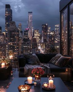 a living room filled with lots of furniture and candles in front of a cityscape