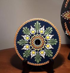 an artistically painted vase sitting on top of a wooden table next to another decorative object