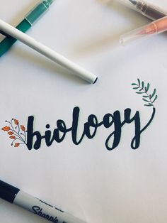 the word biology written in cursive writing next to markers and pens