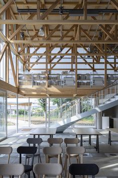 the inside of a building with tables and chairs under a wooden structure that is suspended from the ceiling