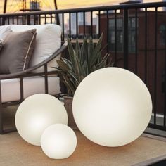 three white balls sitting on top of a table next to a potted pineapple