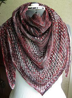 a red and gray knitted shawl sitting on top of a mannequin