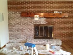 a brick fireplace in the middle of a living room being remodeled with paint and wood