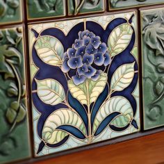 decorative tiles with blue flowers and leaves are displayed on a shelf in a home or office