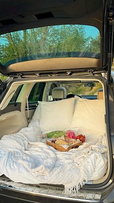 the trunk of a car is filled with blankets and food