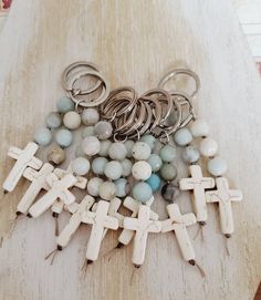 a bunch of beads and cross charms on a wooden table next to a pair of scissors