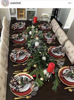 a dining room table set for christmas with place settings and evergreen garland on the table