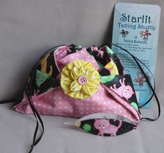 a pink and black polka dot purse with a yellow flower on the front, sitting next to a book