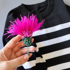 a person holding a pink flower in front of a black and white striped t - shirt