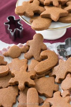 gingerbread cut out cookies sitting on a plate with cookie cutters next to them