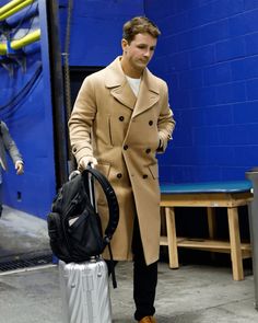 a man in a trench coat pulling a suitcase