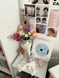 a vase filled with flowers sitting on top of a white table next to a cd player