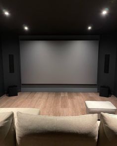 an empty theater room with two couches and a projector screen in the background