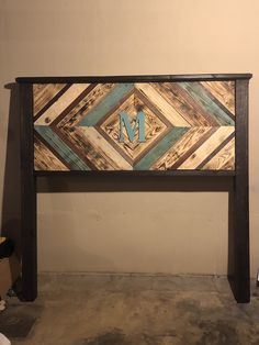 a wooden headboard with the letter m painted on it's side in blue and brown