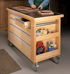 a man standing in front of a workbench with tools on the top and drawers