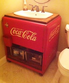 a bathroom with a sink, toilet and coca - cola cooler