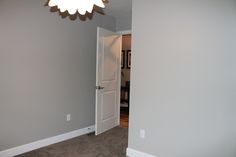 an empty room with a white door and light fixture hanging from the ceiling in front of it