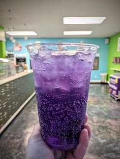 a hand holding up a purple drink in a store