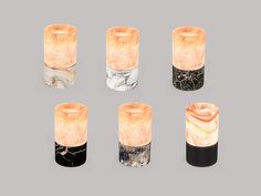 six marble candle holders in different shapes and sizes on a grey background, each with an orange light