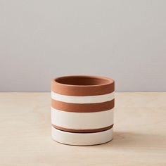 a brown and white striped pot sitting on top of a wooden table