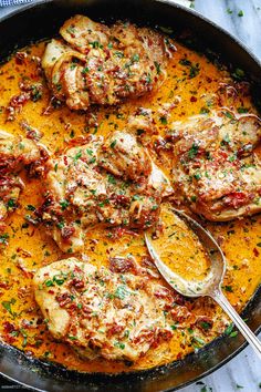 a skillet filled with chicken covered in sauce and garnished with parsley