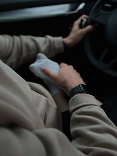 the man is driving his car while holding something in one hand and steering wheel with both hands