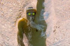 a man swimming in the water wearing a white hat and goggles with his arms up