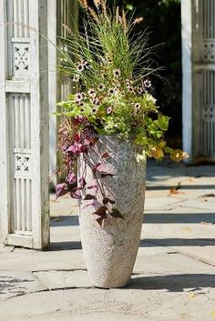 a large planter filled with lots of flowers sitting on top of a cement floor